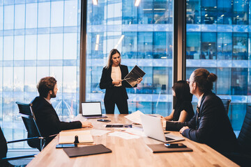 Confident woman explaining project to group of colleagues