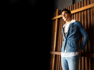 Handsome young man posing on vintage dark  background. Portrait of satisfied Asian man against  wall. Close up face of fashionable Asian man on wall background.