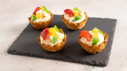 healthy cakes with cottage cheese and fruit in oatmeal baskets on a black board and a white background. cupcakes