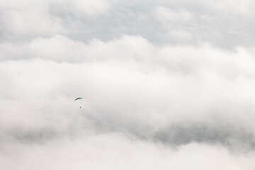 The paraglider flies in the air above the clouds against the backdrop of fluffy clouds