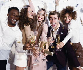 Young People Having Party Holding Champagne Glasses Near White Wall