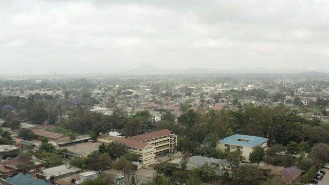 Aerial shot Arusha Tanzania. Drone flight over the streets of the city where you can see old houses, slums and downtown with skyscrapers, and against the background of mountains in the clouds.
