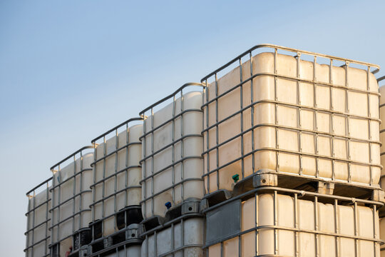 white ibc container in outdoor stock yard of factory, white plastic chemical tanks.