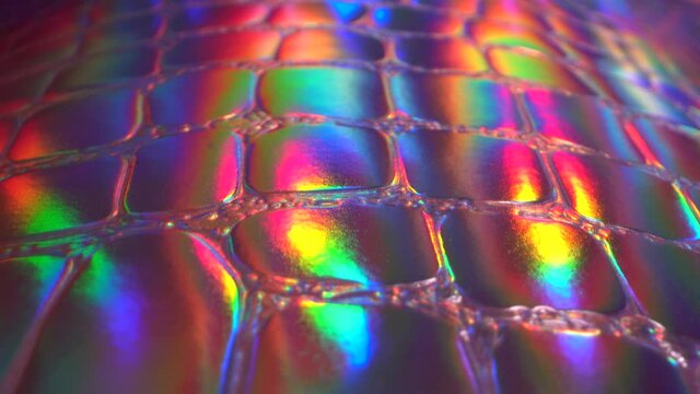 Rainbow iridescent texture close up. Exotic leather imitation. Holographic pink neon purple ultraviolet metallic background