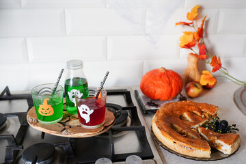 happy Halloween with pumpkin pie and drinks in the kitchen