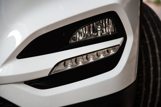 clean white headlight of a new white luxury car. Close-up of the front left headlight.  Free space on right side for text.