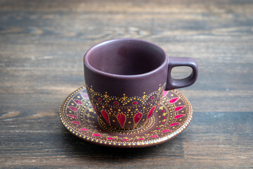 Decorative ceramic painted cup and saucer on wooden background, close up