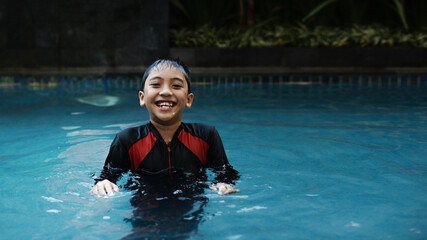 Happy boy kid in swimming pool. Asian kid