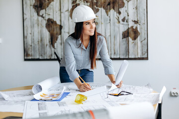 Young, pretty architect woman, working in the office, making drawings