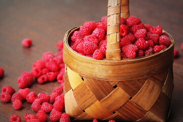 Fresh red raspberries in the basket on wooden background