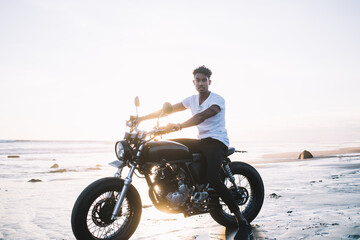Fototapeta na wymiar Confident motorcyclist with motorbike during sunset