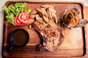 Top view of roasted kurobuta pork chop with sauteed mushroom, potato wedges and black pepper gravy...