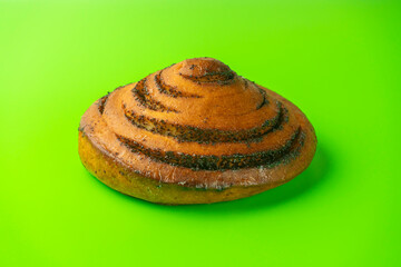 bun with poppy seeds on a green background close-up. isolate
