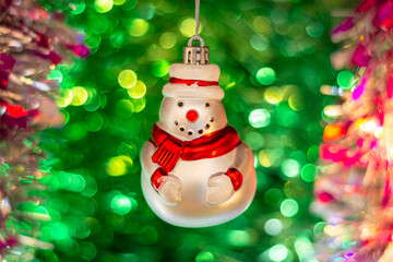 Vintage glass Soviet New Year's toy (snowman) against the background of a Christmas tree and colorful bright tinsel.