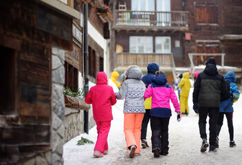 Group of teenager tourists walking on street of mountain resort town in Switzerland, Europe. Winter vacation. Ski resort.