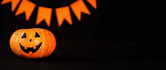 Jack O Lantern Halloween pumpkin with witches hat on wooden table over dark background