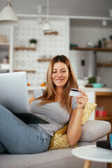 Obraz premium Young businesswoman at home makes a purchase on the Internet. Beautiiful woman on the laptop with credit card