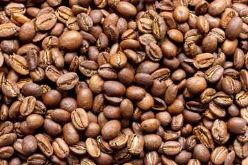 Roasted arabica coffee beans scattered in a heap on the table.
