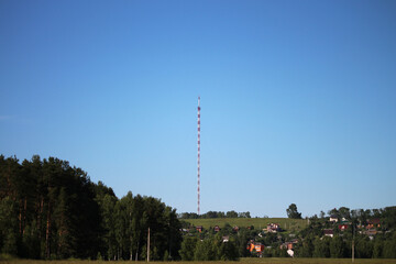 Radio tv tower with guy wires against clear deep blue sky, close up. Red and white lattice design...