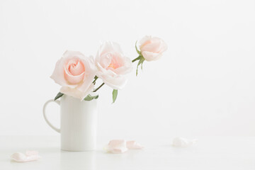 pink roses in white cup on white wooden table