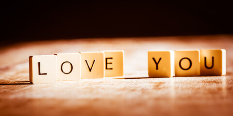 Love you word made of tiles on dark wooden background