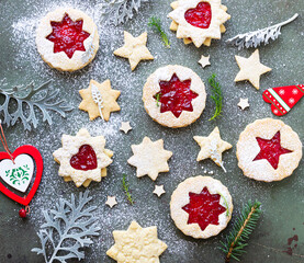 Traditional Linzer Christmas cookies with raspberry jam on green stone background. Flat lay. Festive decoration.