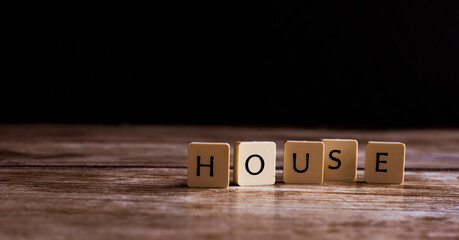 House word made of tiles on dark wooden background