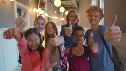 Happy diverse kids students with thumbs up at school