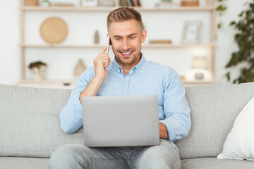Portrait of successful smiling man talking on cellphone using pc