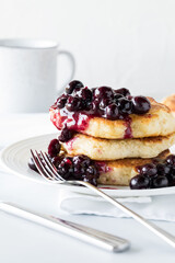 Warm blueberry sauce on top of a fluffy pancake stack ready for eating.