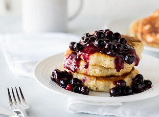 Delicious fluffy pancake stack with warm blueberry sauce ready for eating.