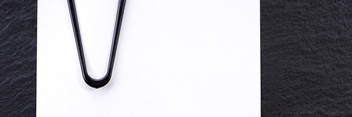 Blank white paper with paper clip on black background, Panoramic image