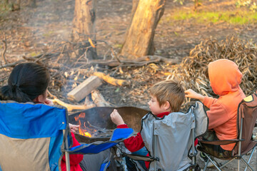 Kids burning fire at Kuitpo forest camping ground while their mother relaxing in the chair during school holidays