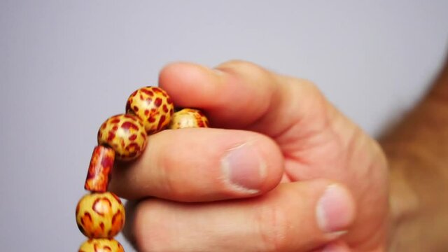 Close up of a young mans hand fingering a beautiful wooden rosary