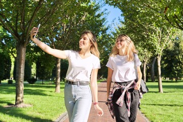 Two happy teenage girls looking at webcam of smartphone