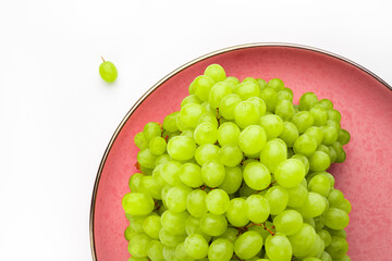 Green grapes on pink platter on white background horizontal with copy space