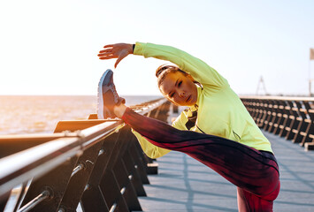 outdoor workout concept. young woman in tracksuit performs sports workout on the pier