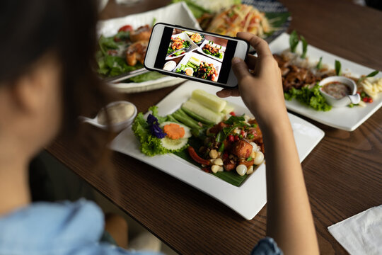 Woman photographing food by smartphone. Woman taking pictures of a delicious lunch in a restaurant to pop upload in a social media. The concept of using a mobile phone, taking photo