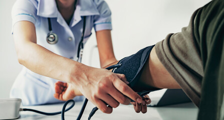 Nurse measuring arterial blood pressure man patient in hospital. Health care concept