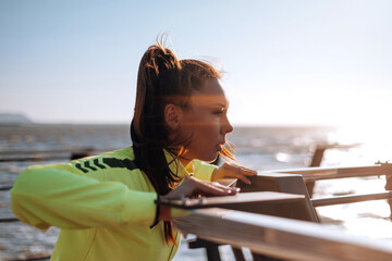outdoor workout concept. young woman in tracksuit performs sports workout on the pier