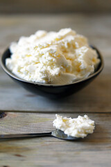 Fresh mascarpone cheese in a bowl on a wooden surface. Selective focus. Macro.