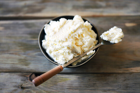 Fresh mascarpone cheese in a bowl on a wooden surface. Selective focus. Macro.