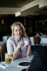 Beautiful businesswoman dressed in the suit drinking coffee. Businesswoman enjoying in the restaurant.