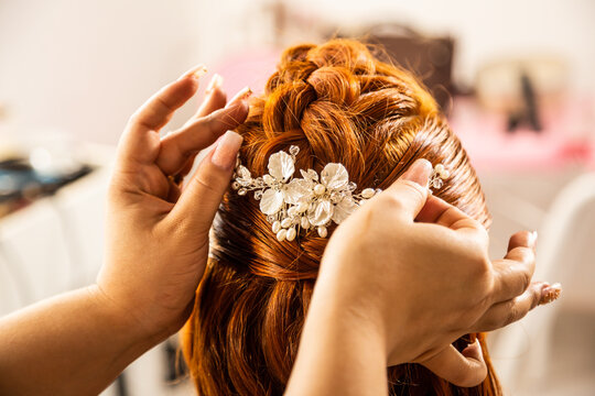 Close nas m&atilde;os da cabeleireira fazendo um penteado em cliente.
