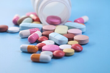 close up of colorful pills spilling on blue background 