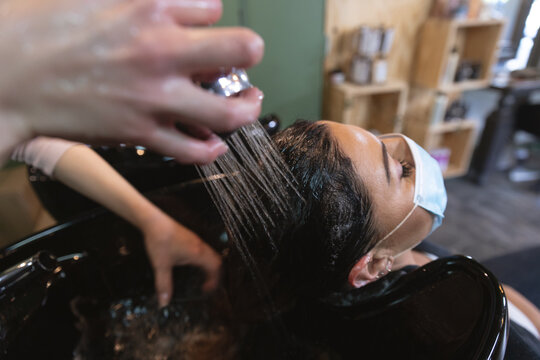 Female hairdresser washing hair of female customer at hair salon