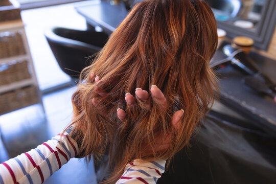 Female hairdresser going through hair of female customer with her fingers at hair salon