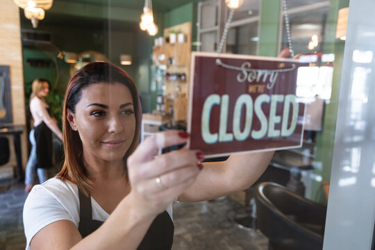 Female hairdresser holding Closed sign board at hair salon