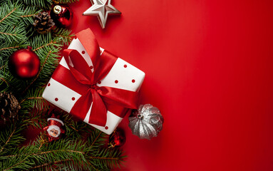 Christmas composition on a red background with a white gift box, with a red ribbon with fir...