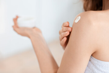 Closeup of unrecognizable woman applying body cream on her shoulder
